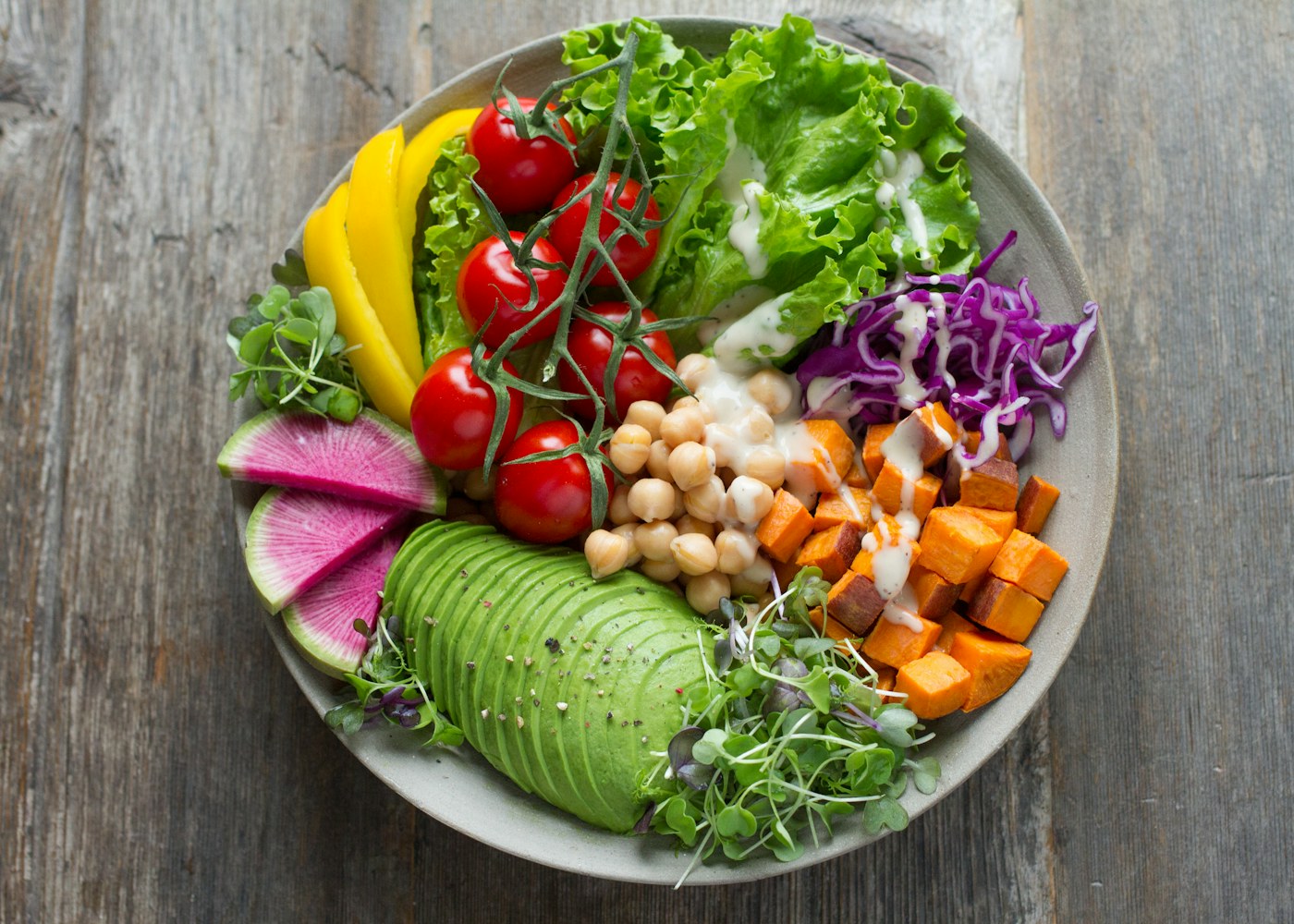 A colorful nourish bowl of fresh whole foods, greens, chickpeas, and roasted sweet potato